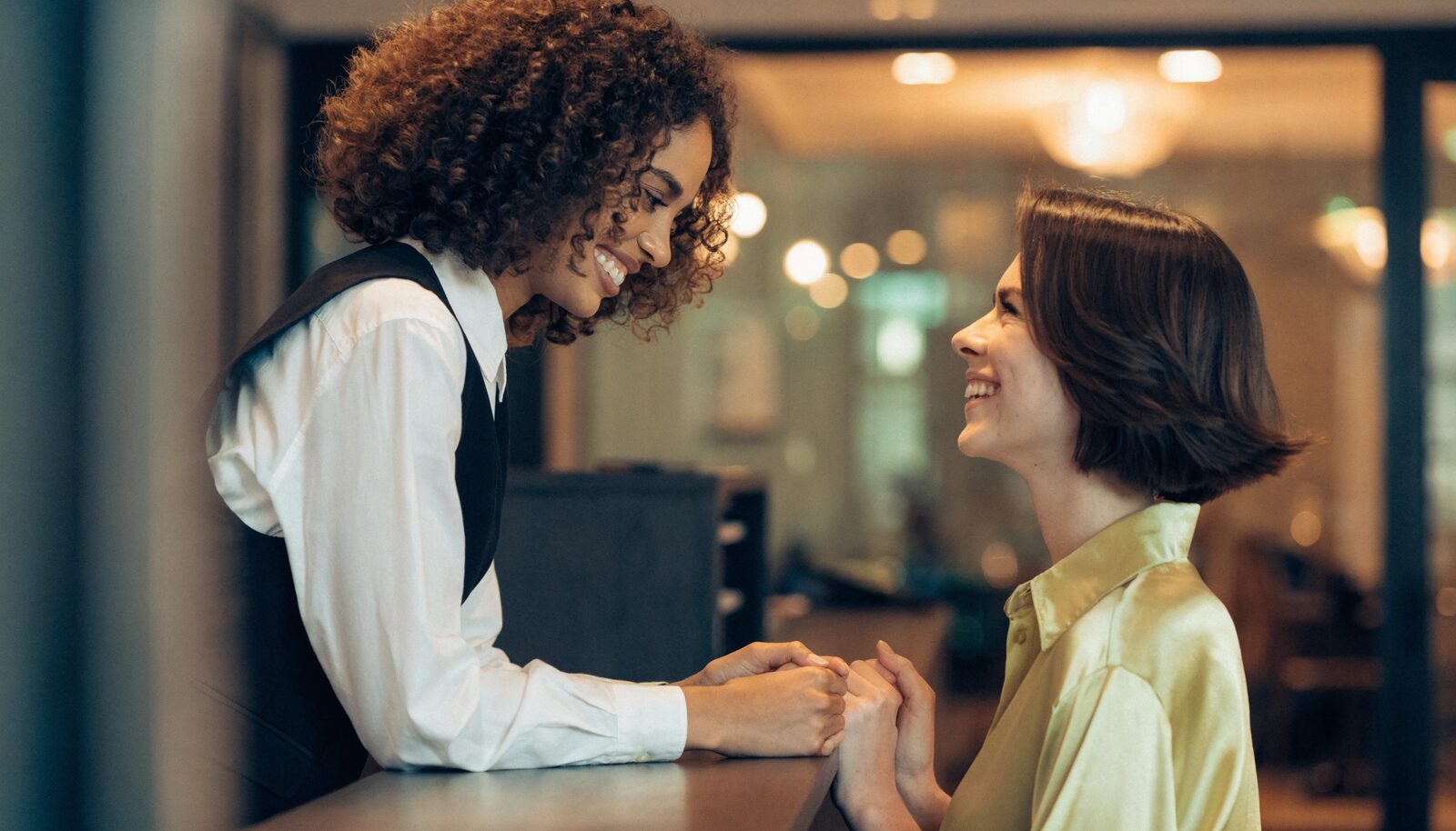 Parrucchiera che accoglie con un sorriso una cliente affezionata alla reception