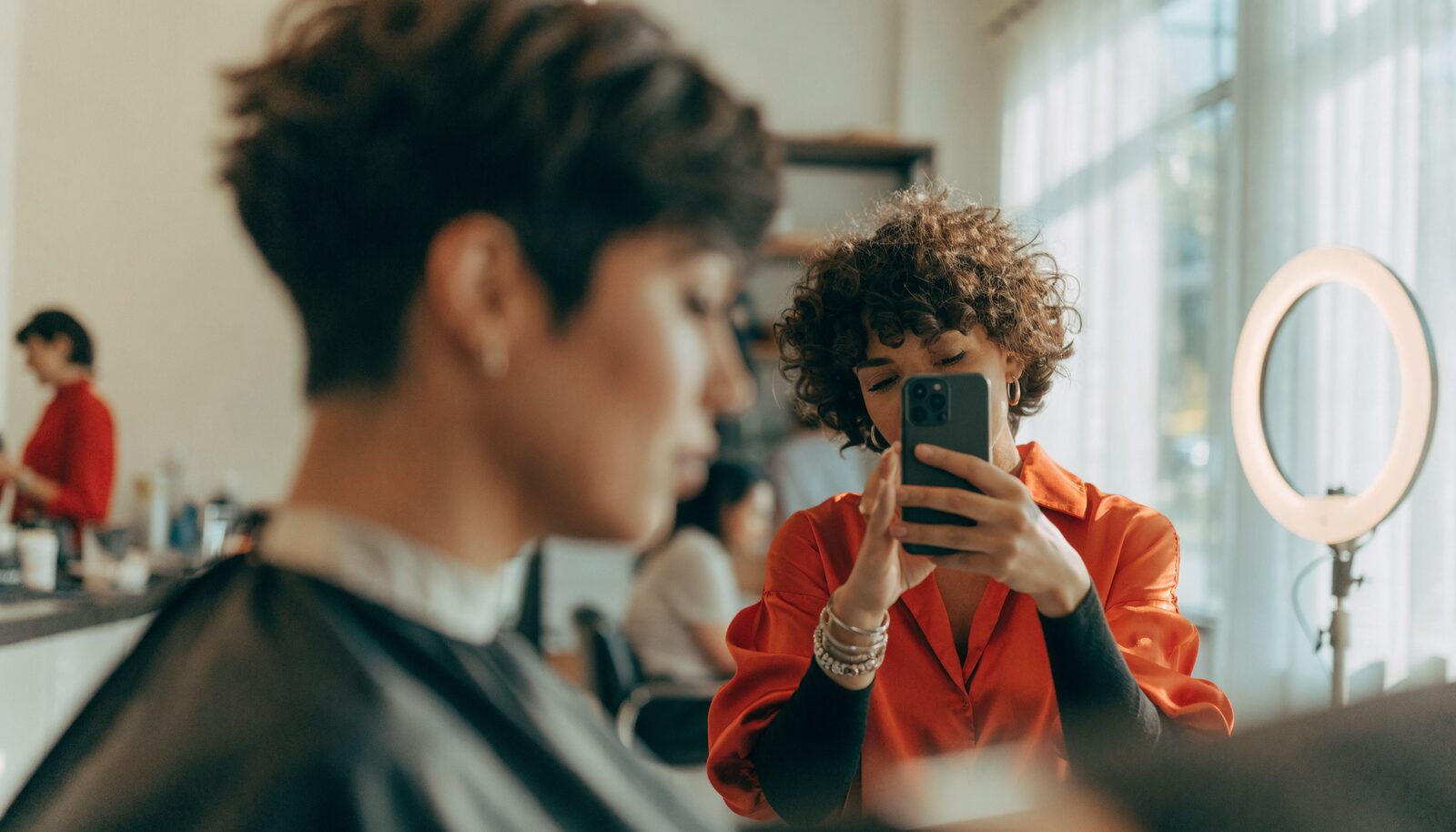 Parrucchiera che fotografa con lo smartphone un'acconciatura appena finita per i social