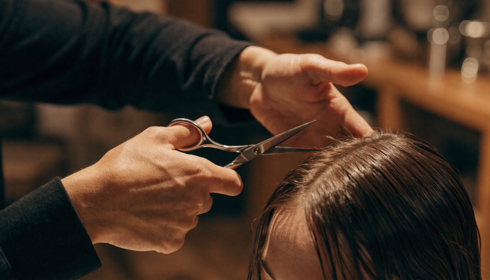 Mani di un parrucchiere professionista che tagliano i capelli con le forbici